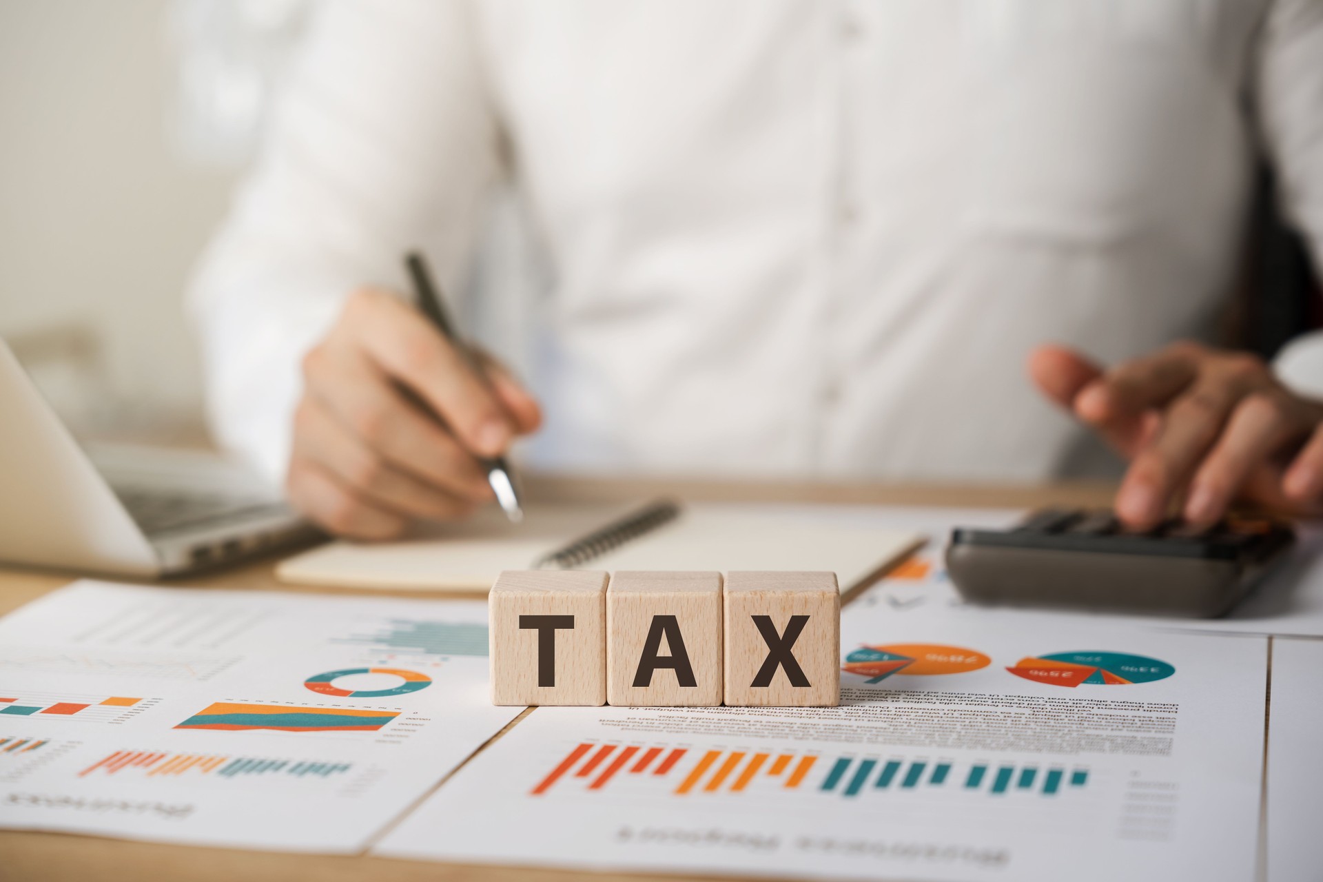 Corporate and individual tax payment concept, businessman taking note of personal income tax deduction, VAT and property tax of business.